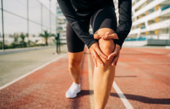 sport woman holding knee with hands in pain